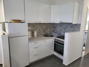 a white kitchen with white cabinets and a sink at Apartman Ane in Slano