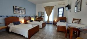 a room with three beds and a table and chairs at Aegean Star Hotel in Karavostasi
