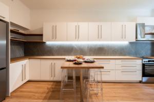 a kitchen with white cabinets and a wooden table at 4BD Apartment with Outdoor Jacuzzi Garden in Athens