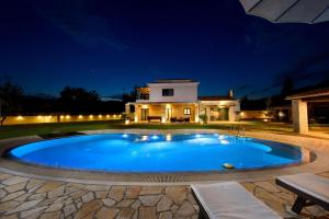 a large blue swimming pool in front of a house at Villa Black White Dassia in Dassia
