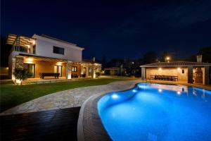 a swimming pool in front of a house at night at Villa Black White Dassia in Dassia