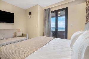 een slaapkamer met een bed, een bank en een televisie bij Grande Mare with Sea view in Amoudara Herakliou