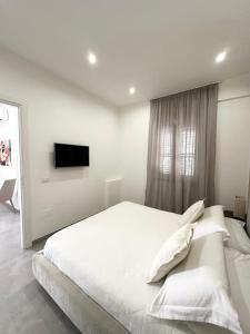 a white bedroom with a large bed and a television at Petra Maris B&B in Peschici