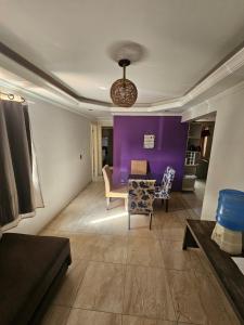 a living room with a purple wall and a table and chairs at Apartamento Cantinho na Praia in Ilhéus