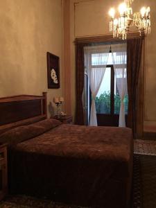 1 dormitorio con cama, ventana y lámpara de araña en Hotel Boutique Casa de la Palma en Puebla