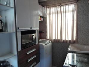 a small kitchen with a sink and a microwave at Apartamento Cantinho na Praia in Ilhéus +4 photos