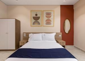 カイロにあるTravelholic 90 Residenceのベッドと壁に2枚の絵が飾られた寝室 +59枚の写真