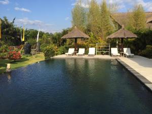 a pool with chairs and umbrellas in a yard at Villa Danison in Umeanyar