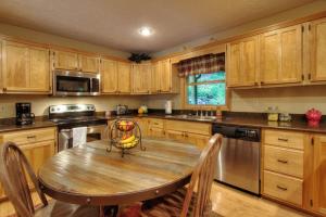 eine Küche mit Holzschränken und einem Holztisch in der Unterkunft Gorgeous "Country Roads" by HoneyBearCabins 4BR 4BA, next to pool, easy drive, main strip location! in Pigeon Forge + 33 Fotos