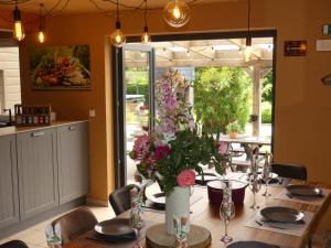 une salle à manger avec une table avec un vase de fleurs dans l'établissement Coeur de Loup, à Sourbrodt