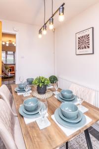 a dining room with a wooden table with plates and glasses at Central Birmingham Luxury House, Sleeps 6 people - 10 mins from Solihull NEC, JLR, BHX Airport, Resorts World in Birmingham +22 photos