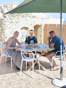 a group of people sitting at a table under an umbrella at Il figolla farmhouse in Xagħra