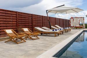 a patio with chairs and an umbrella next to a pool at Ella in Velika