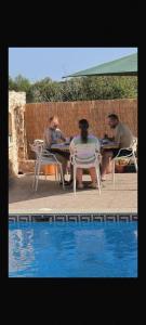 a group of people sitting around a table by a pool at Il figolla farmhouse in Xagħra
