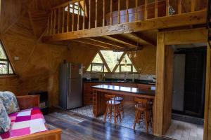 a kitchen and living room of a log cabin at Hermoso domo en altura entre el bosque nativo + tinaja privada in Licán Ray