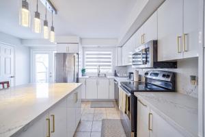 a white kitchen with white cabinets and a sink at 3 Bedrooms Townhouse Near Square One, Ridgeway Plaza & Toronto Airport with 2 Parkings in Mississauga