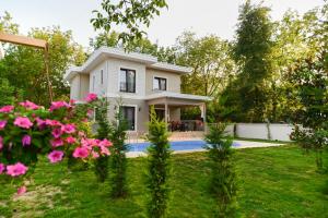 a white house with pink flowers in the yard at Guzel Evler Family Resort in Sapanca