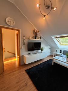 a living room with a tv and a clock on the wall at Privatunterkunft Am Aaper Wald in Düsseldorf
