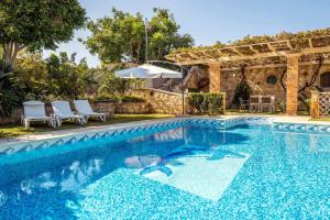 a pool with an umbrella and chairs and a patio at Niko's art Villa in Chania in Perivólia
