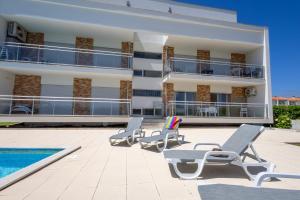 um edifício com espreguiçadeiras ao lado de uma piscina em Carmona A T2 - By Smarthomes em São Martinho do Porto