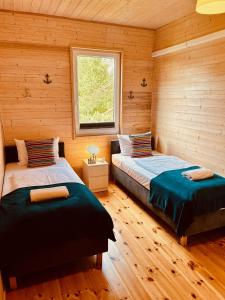 two beds in a room with wooden walls at Rafa Międzywodzie in Międzywodzie