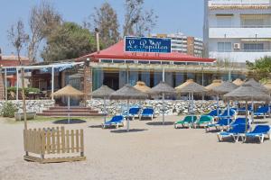 a group of chairs and umbrellas in front of a building at Apartamentos Coronado in Marbella