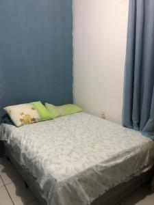 ein kleines Bett in einem Zimmer mit blauen Vorhängen in der Unterkunft Casa da Mari in Petrolina