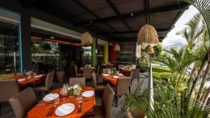a restaurant with tables and chairs and plants at Rincon del Valle Hotel & Suites in San José
