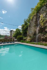 a swimming pool with a waterfall in the background at Pensiunea Apuseni Wild in Remeţi
