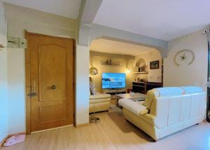 a living room with a white couch and a television at Apartamento Vergel botica Suite in San Martín de Valdeiglesias