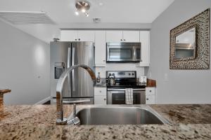 Una cocina con fregadero y frigorífico de acero inoxidable. en Fabulous 2 bedroom in Heart of Grove, en Miami