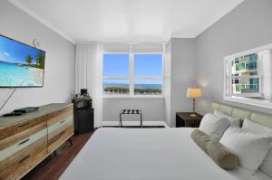 Un dormitorio blanco con una cama grande y un televisor. en Fabulous 2 bedroom in Heart of Grove, en Miami