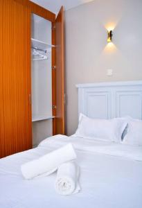 Un dormitorio con dos camas con sábanas blancas y un armario. en Mels Cosy Homes, en Nairobi