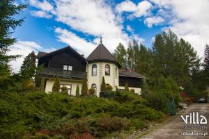 a house with a black roof on a hill at Villa Falsztyn Holiday Home in Falsztyn