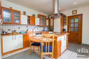 - une cuisine avec des placards en bois, une table et des chaises dans l'établissement Villa Falsztyn Holiday Home, à Falsztyn