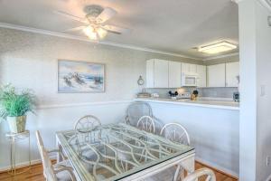 a kitchen with a dining table with chairs and a ceiling fan at Sweet Serenity #2A in Topsail Beach