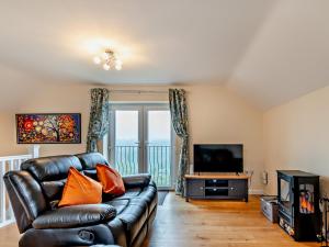 a living room with a leather couch and a television at 2 Bed in Cinderford 94754 in Cinderford