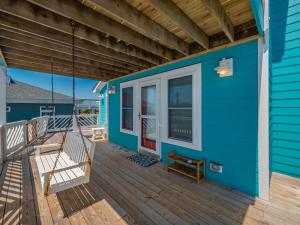 a porch of a blue house with a swing at The Water Bear in Topsail Beach