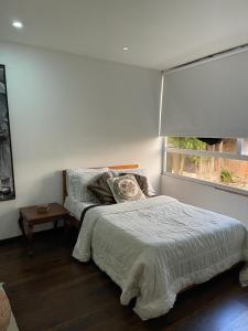 Una habitación blanca con una cama y una ventana en Habitación El Silencio - Athos Hotel B, en Bolivia