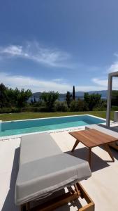 a table and a bench next to a swimming pool at Cavalier Suites Nikiana Lefkada AV Properties in Nikiana