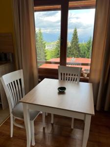 a white table and two chairs and a window at Роси Студио Банско in Bansko