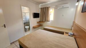 a small room with a bed and a bathroom at diRoma Fiori - Apartamentos JN in Caldas Novas