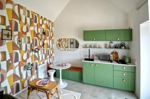 a kitchen with green cabinets and a colorful wall at La petite maison de Celestine in Plonéour-Lanvern