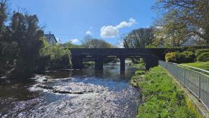 eine Brücke über einen Fluss mit Felsen im Wasser in der Unterkunft Seafront House in Sligo