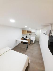 a white room with a bed and a kitchen at MEDELLIN CÓMODOS APARTAESTUDIOS in Medellín