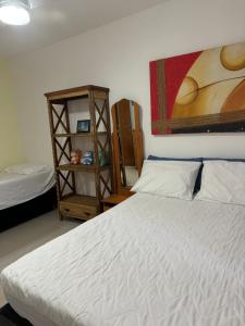 a bedroom with a white bed and a book shelf at Casa praia dos anjos com piscina in Arraial do Cabo +26 photos
