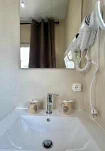 uma casa de banho com lavatório, secador de cabelo e espelho em Residencial Duque de Saldanha em Lisboa