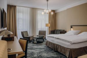 a hotel room with a large bed and chairs at Esplanade Carlsbad in Karlovy Vary +37 photos
