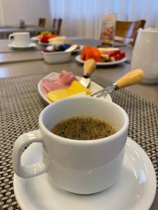 a cup of coffee on a plate on a table at Promenade Fusion Itaguaí in Itaguaí
