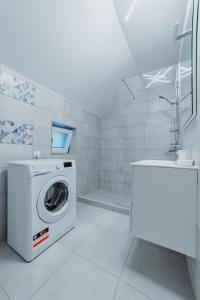 a white bathroom with a washing machine and a sink at Villa Russo in Râşnov